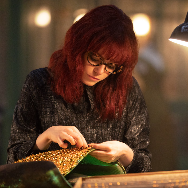 Emma Stone as Cruella wears glasses in Disney's Cruella, designed by Tom Davies.